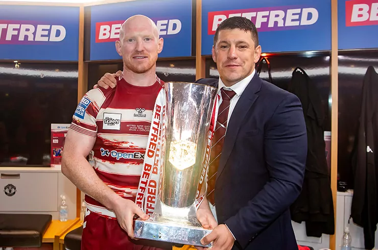 Two Wigan Warriors rugby players posing with a trophy